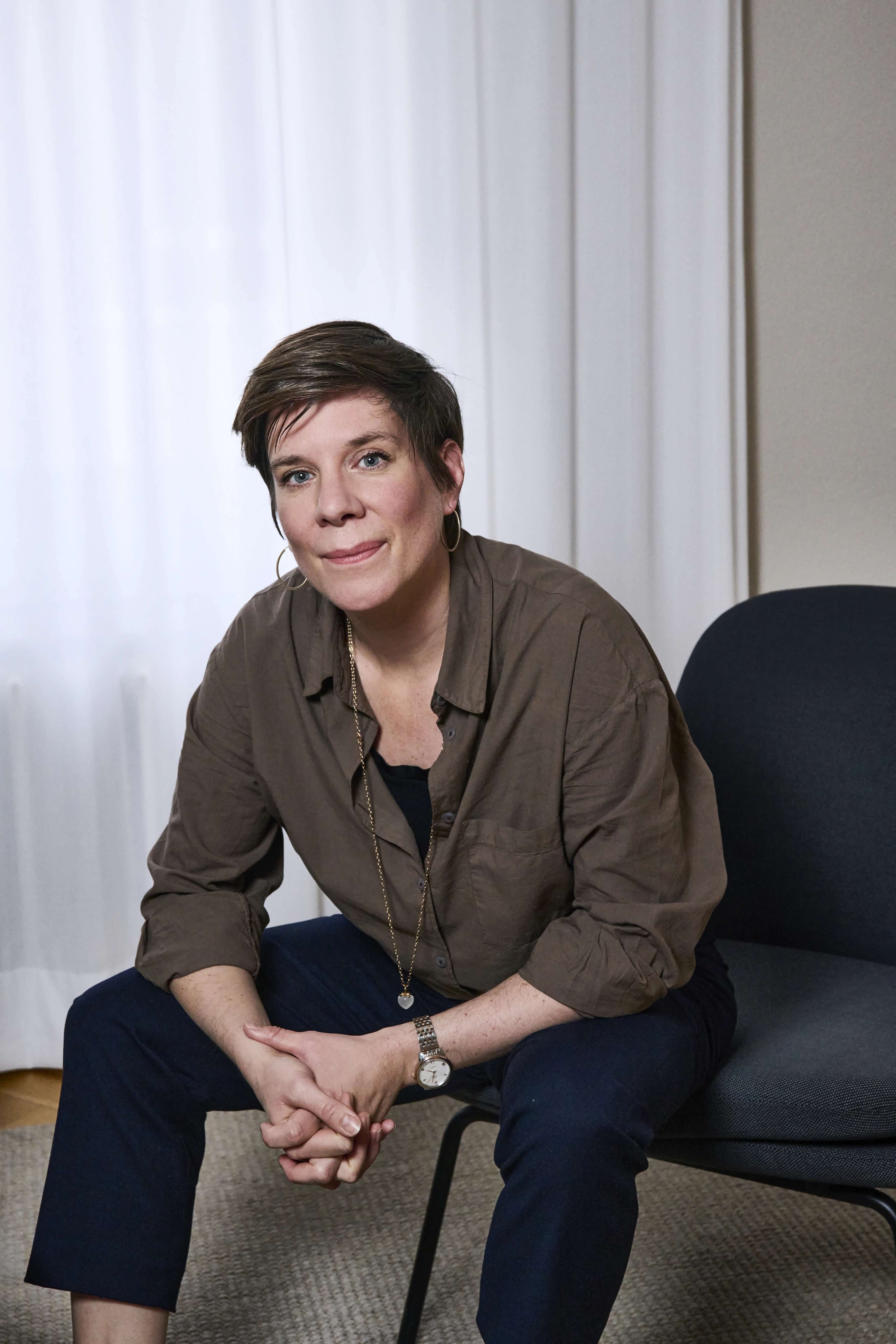 Nina Gubser sitzt entspannt auf einem Stuhl in ihrer Praxis