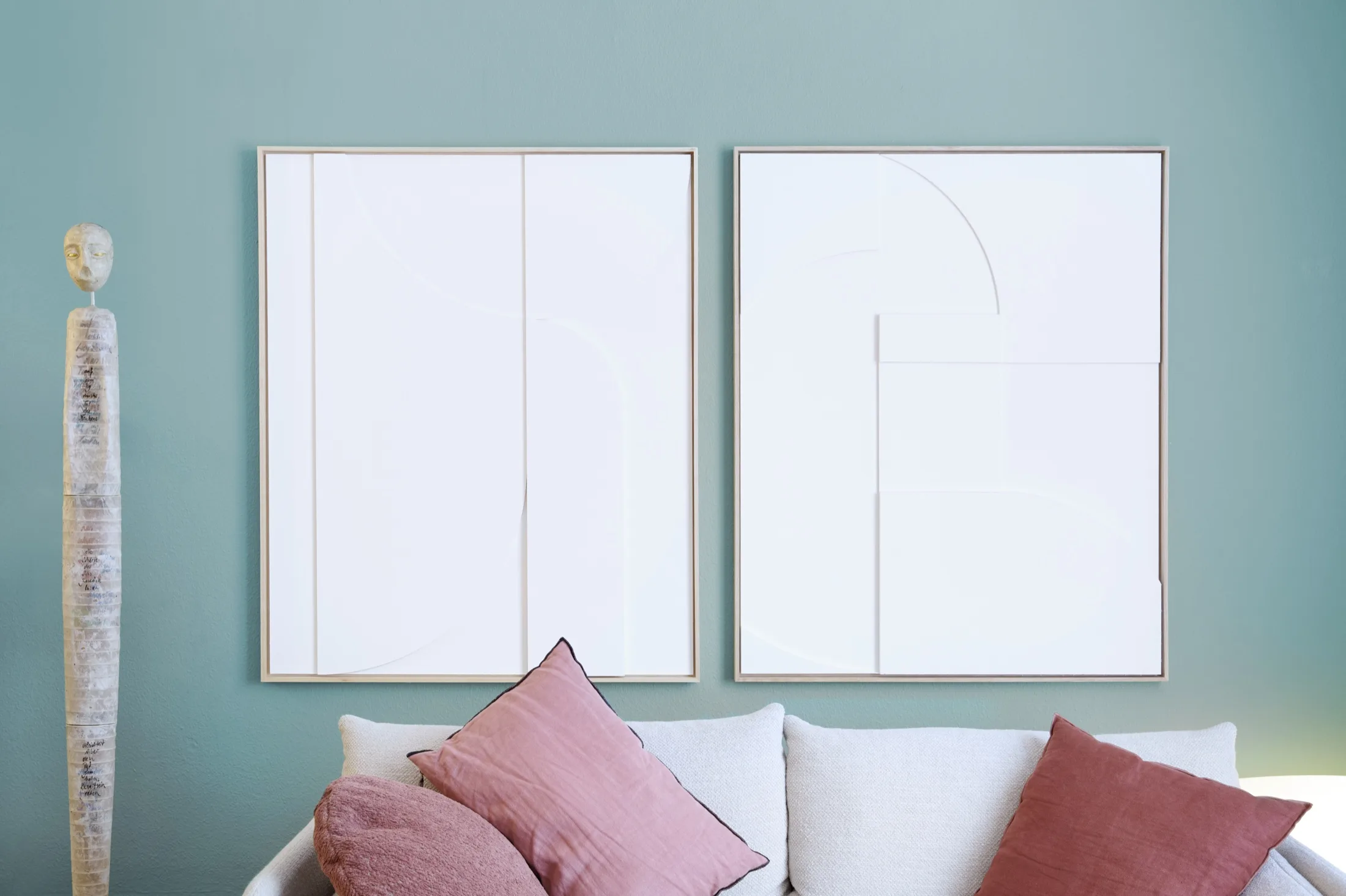 Zwei minimalistische Bilder und eine Skulptur an der mintgrünen Praxiswand