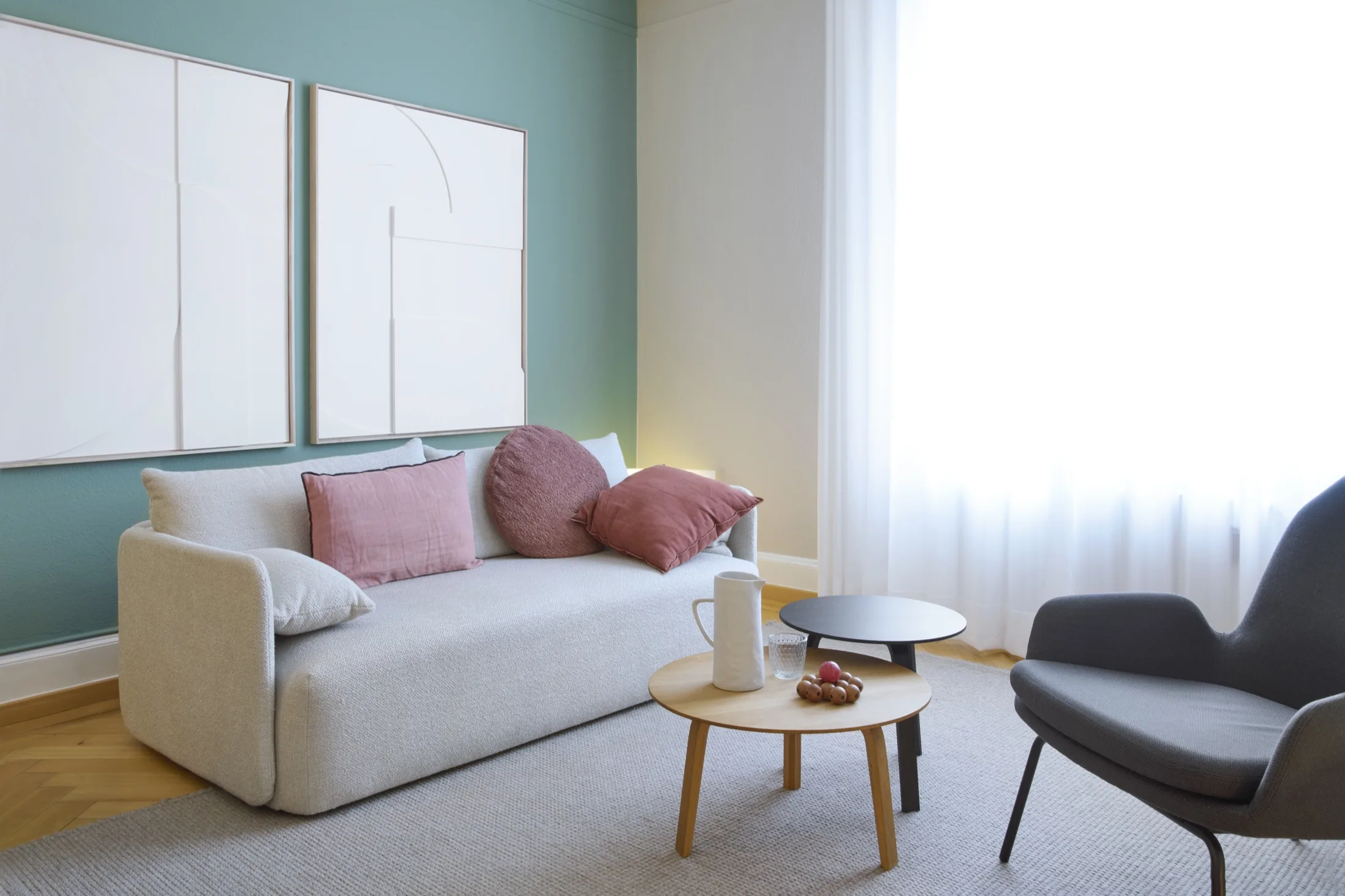Weisses Sofa mit altrosa Kissen an grüner Wand im Therapieraum